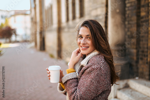 Young woman in the street drinking coffee.
