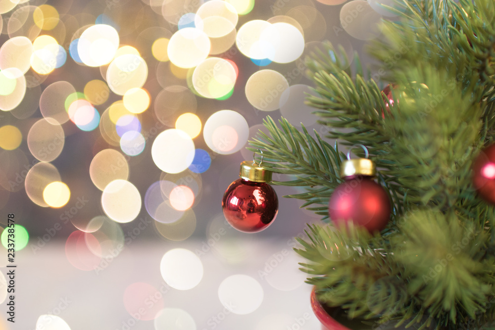 Closeup of red bauble hanging from a decorated Christmas tree. Retro filter effect.