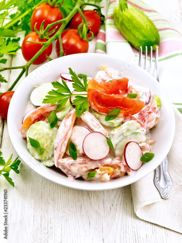 Salad from fresh vegetables in plate on light board