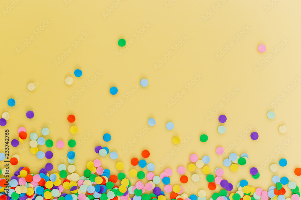 Colorful confetti on yellow background.