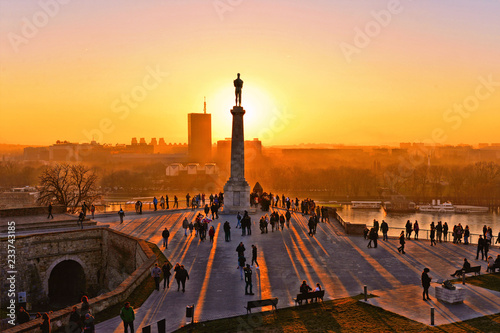 Sunset light on Danube river, statue and silhouettes of people in fortress Kalemegdan in Belgrade Serbia