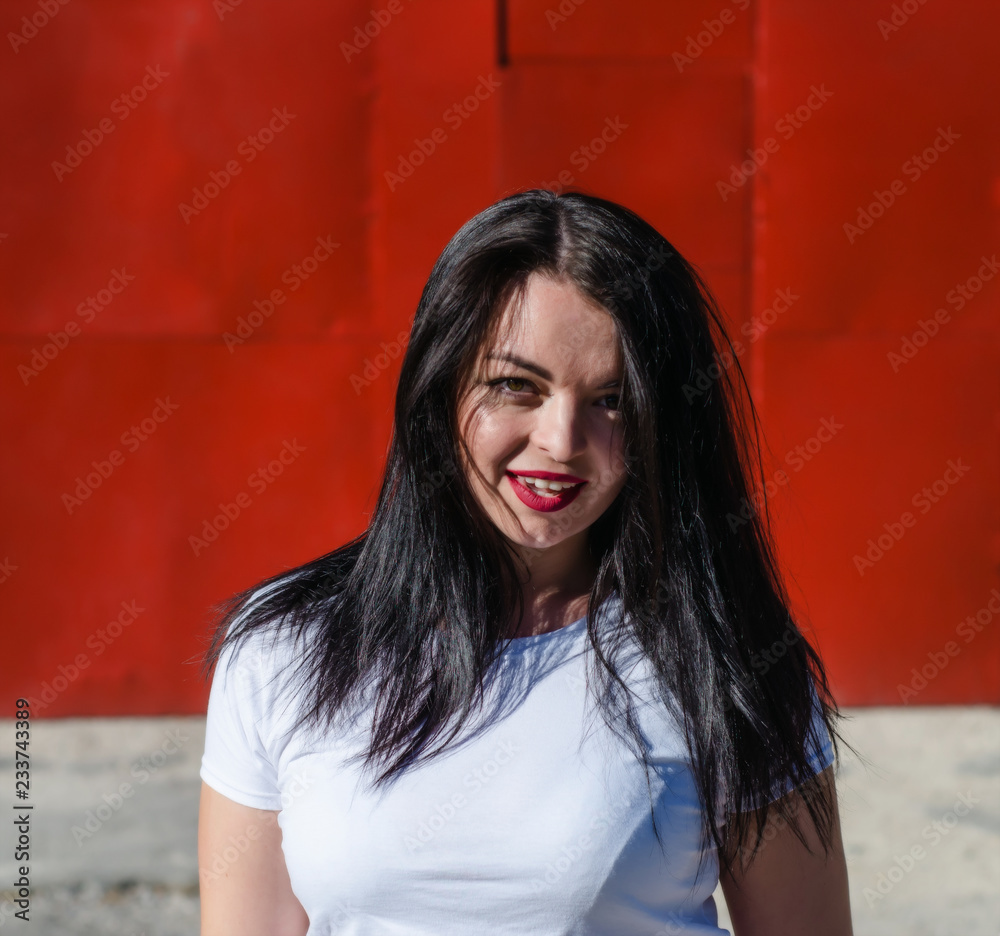 Fototapeta premium Attractive girl with black hair smiling. Red background.