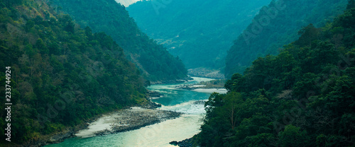 Spectacular view of the sacred Ganges river flowing through the green mountains of Rishikesh, Uttarakhand, India.