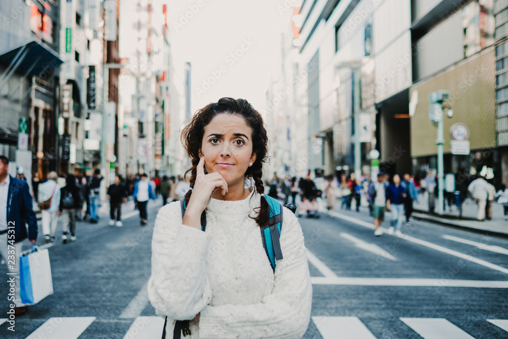 .Caucasian middle-aged woman traveling through Japan. Touring the city of Tokyo in one of the neighborhoods with more shops. Crowded place. Lifestyle.