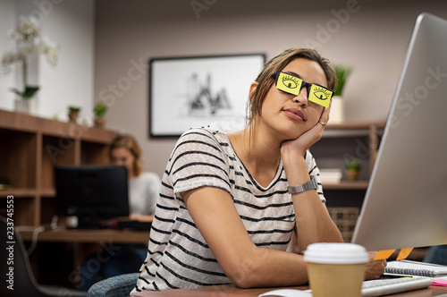 Tired woman covering eyes with post it photo