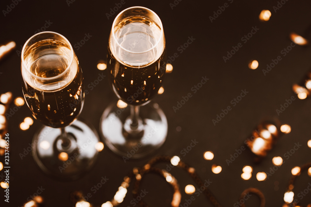 Two glasses of champagne with golden decoration on black elegant background. Top view, place for text. Festive concept.