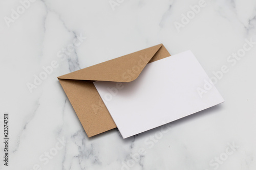 Blank white card with kraft brown paper envelope on marble background photo
