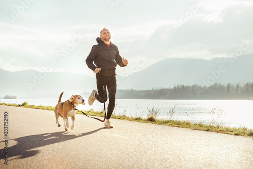 Obraz na płótnie Morning jogging with pet: man runs together with his beagle dog