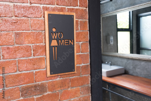 Women signs on public restroom on brick wall