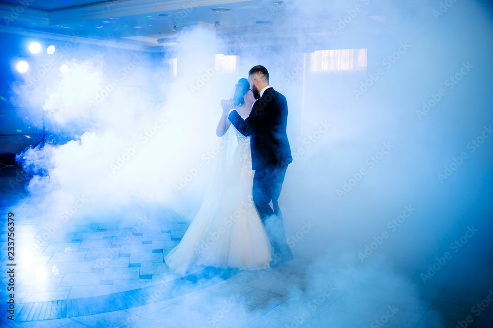 The first dance of newlyweds in blue smoke