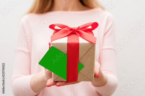 Woman holding a box with a gift, business card to the camera, front view, close up, background with copy space, for advertising or slogan © Анастасия Семашко