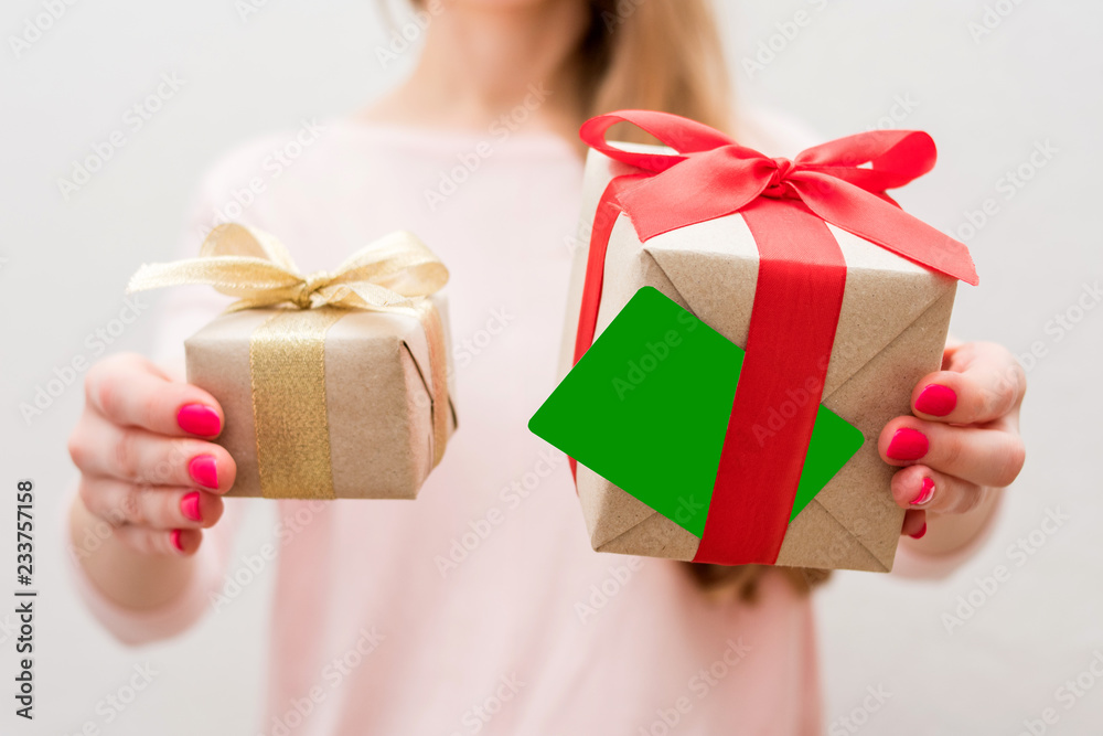 Woman holding a box with a gifts and business card to the camera, front view, close up, background with copy space, for advertising or slogan Woman holding a box with a gifts and business card to the camera, front view, close up, background with copy space, for advertising or slogan