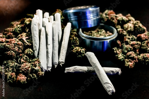 Obraz na płótnie Marijuana joints stacked on a pile of bud with a cobalt coloured bud grinder. w salonie