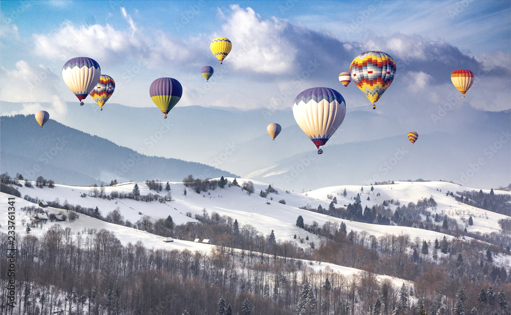 Fototapeta premium Multicolored hot air balloons on a mountain ridge covered snow