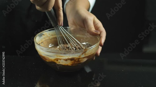 Beat liquid chocolate with a milk whisk over a black background. Cooking desserts, cakes, chocolate icing photo