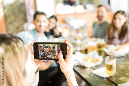 Woman Using Smartphone To Capture Happy Moments With Friends