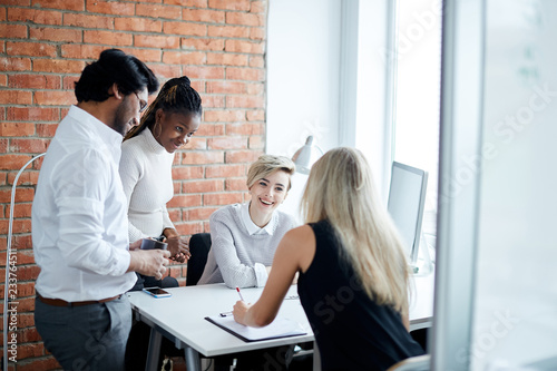 gossiping young office workers. emloyees talling jokes to each other while working photo