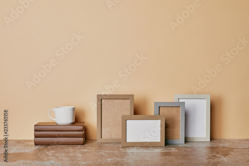 Photo frames  books and cup of coffee on beige background