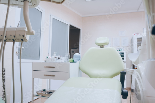 Professional dental unit with green chair and tools. Dentistry, medicine, medical equipment and stomatology concept. White tone.