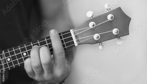 Men hand plaiyng  on ukulele macro black and white photo