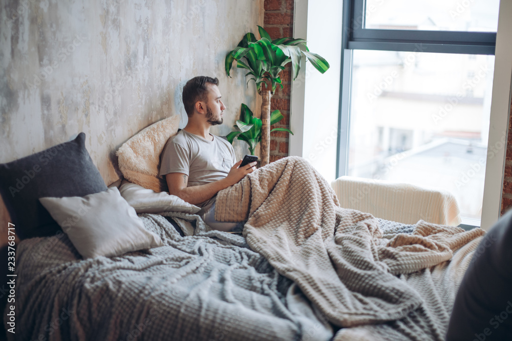 Young gay couple going through relationship problems. Pensive gloomy man  dressed in t-shirt and underwear