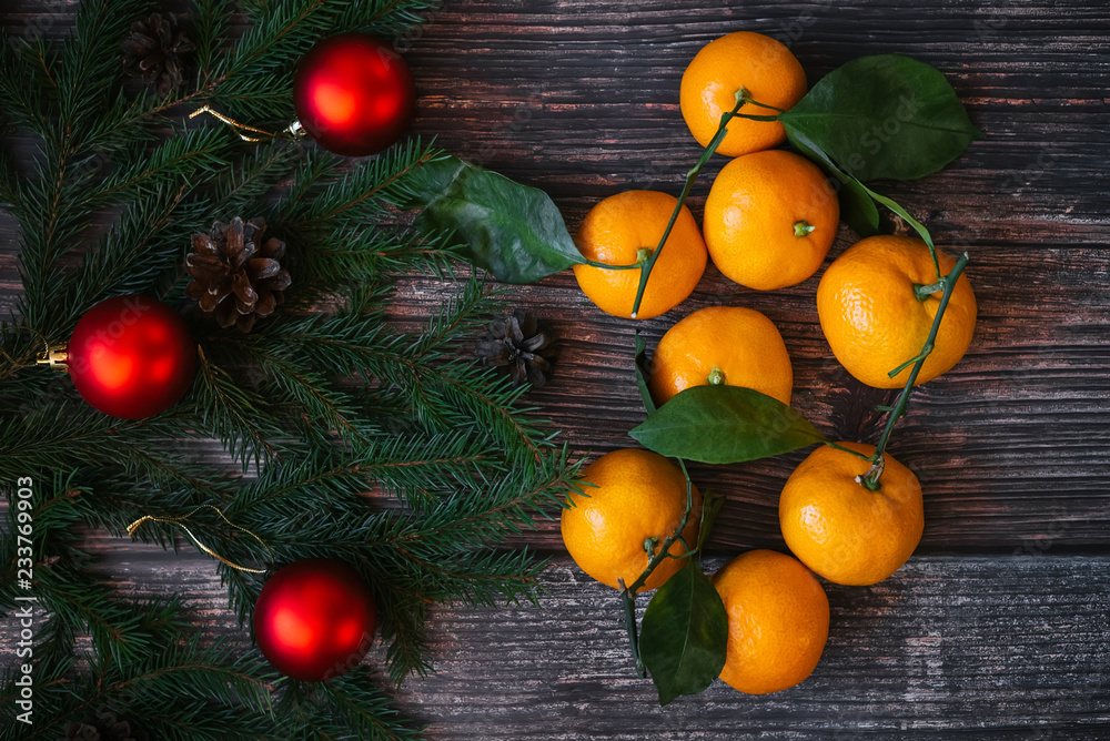 Christmas background with Mandarins, fir branches, red balls and pine cones on wooden table. Traditional festive winter decor for the new year. Flat lay top view Christmas background with Mandarins, fir branches, red balls and pine cones on wooden table. Traditional festive winter decor for the new year. Flat lay top view
