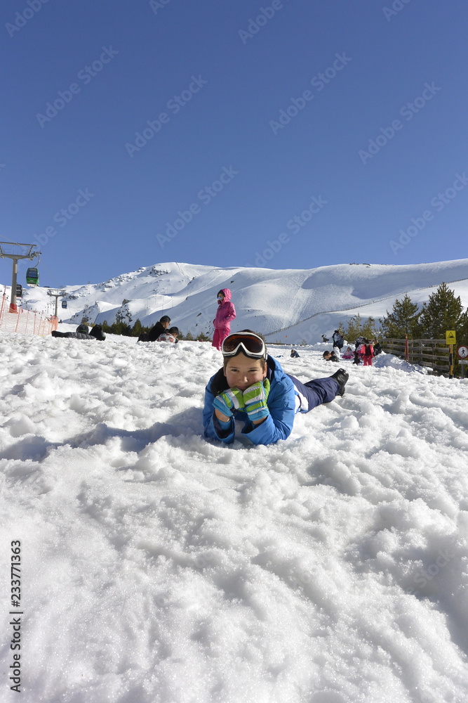 Un chico lindo en un traje de esquí juega bolas de nieve y esculpe un muñeco de nieve. Un chico lindo en un traje de esquí juega bolas de nieve y esculpe un muñeco de nieve.