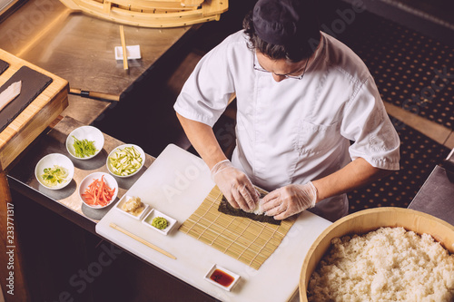 talented male chef decorating sushi, creative work. close up top view shot photo