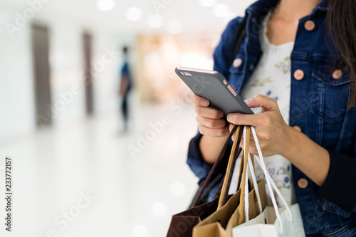 Asian Woman holding shopping bags and using smart phone