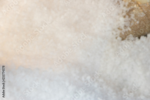 Blurred snow background with a piece of women's festive gold shoe in a corner. Concept: winter celebration party. 