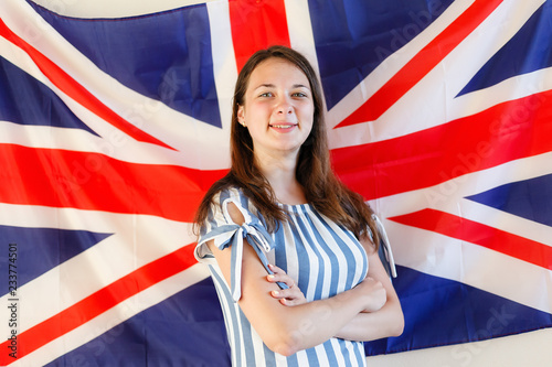 Young woman with flags of English speaking countries. English female student with the British flag at the background. English, learn, studying.