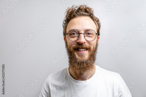 Foto Portrait of young handsome hipster man with beard smiling laughing looking at camera over white background