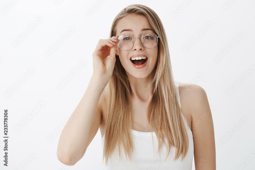 Girl putting on glasses being surprised and happy seeing familiar face in ground, sighing relieved and amazed touching rim of eyewear making impressed and joyful gesture over gray background Girl putting on glasses being surprised and happy seeing familiar face in ground, sighing relieved and amazed touching rim of eyewear making impressed and joyful gesture over gray background
