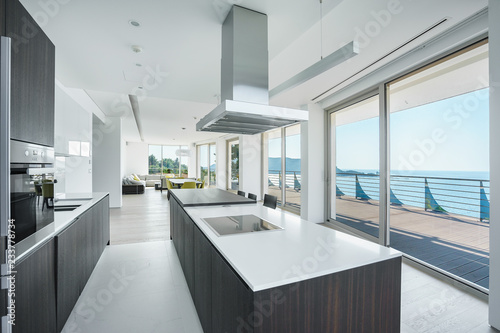 Interior of light spacious kitchen with large panoramic windows in a luxury villa © wolfcub777