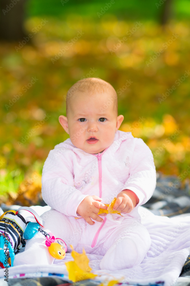 Chubby little baby girl sitting on a rug in a park Chubby little baby girl sitting on a rug in a park