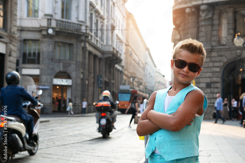 Young boy posing in the milanese street with old tram on background. Cute happy 6 years old boy posing in Milan, Italy. Kid's street fashion. Trendy boy in suit walking.