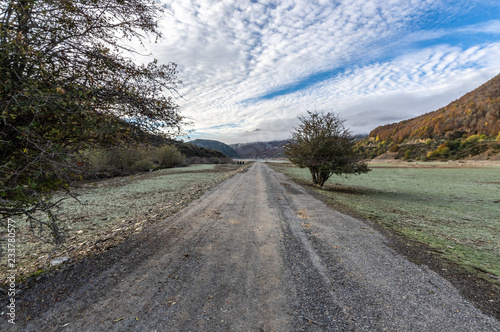 Landscape photography in with two trees one on each side of the ruin road in the middle of a valley that is generally covered by the waters of the reservoir of Riaño, in Leon (Spain). photo