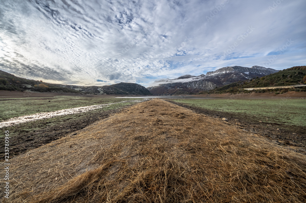 Naklejka premium Old road in ruins that is generally flooded by the waters of the reservoir of Riaño in Leon, Spain. In the background you see the mountains between the morning mists. 