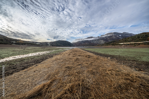 Old road in ruins that is generally flooded by the waters of the reservoir of Riaño in Leon, Spain. In the background you see the mountains between the morning mists.  photo