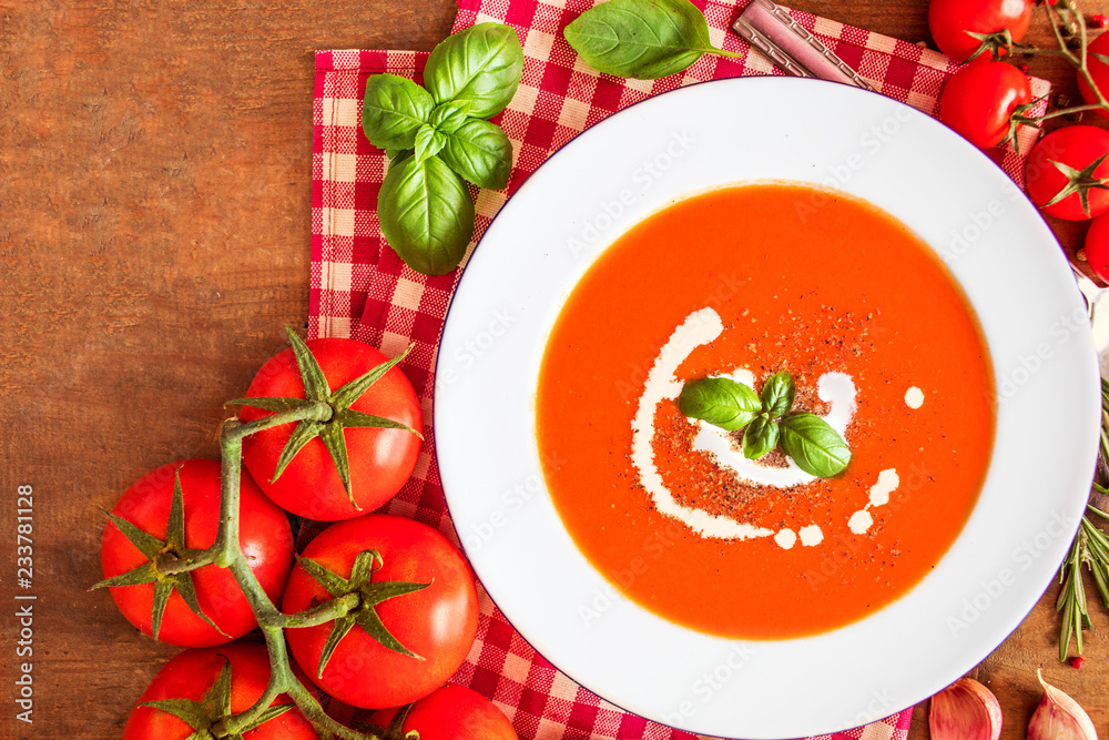 Tomato Soup composition with fresh tomatoes, basil leaf and garlic on a wood table, view from above. Vegetarian Autumn Food Tomato Soup composition with fresh tomatoes, basil leaf and garlic on a wood table, view from above. Vegetarian Autumn Food