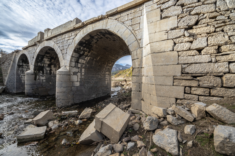 Old bridge in ruins that is generally flooded by the waters of the reservoir of Riaño in Leon, Spain. Yyou can see the fallen stones of the bridge