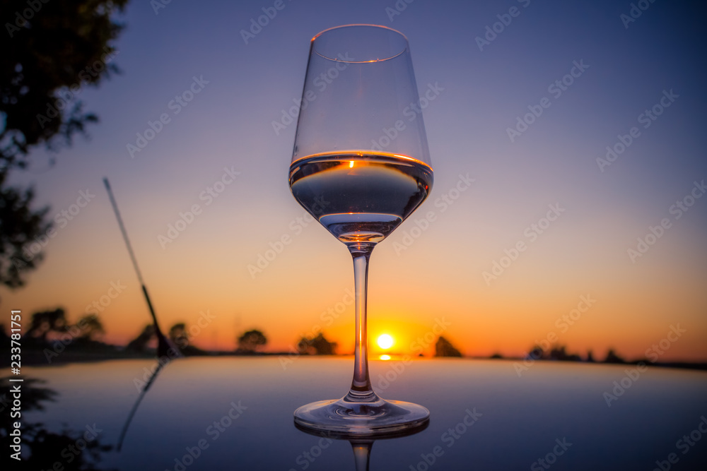 Sunset glass of water on a car roof