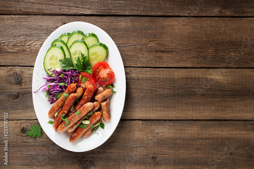 Tasty grilled sausages with vegetable salad in white plate