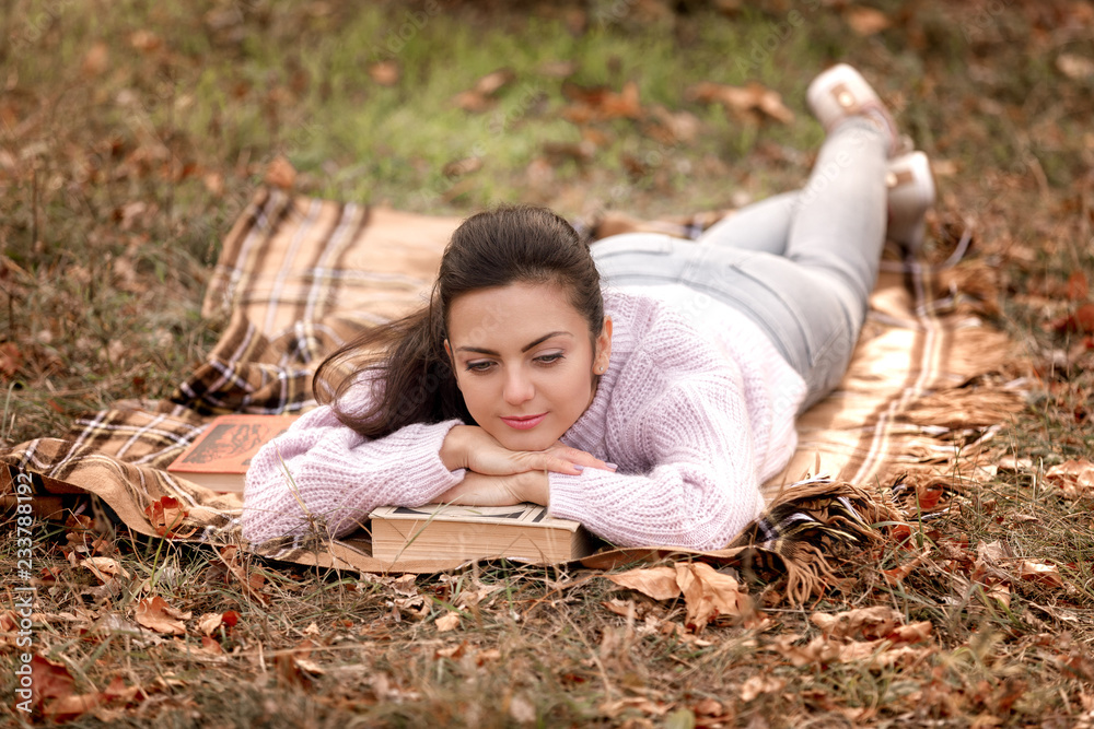 Fototapeta premium woman sitting in autumn park and reading book