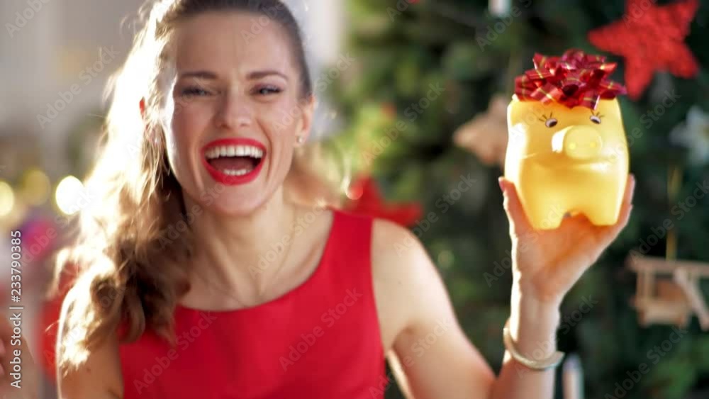 happy stylish housewife in red dress with yellow piggybank near Christmas tree New Year - time for gifts. Start of new fiscal year with happy piggybank!. This video was shot in PRORes 422 codec. happy stylish housewife in red dress with yellow piggybank near Christmas tree New Year - time for gifts. Start of new fiscal year with happy piggybank!. This video was shot in PRORes 422 codec.