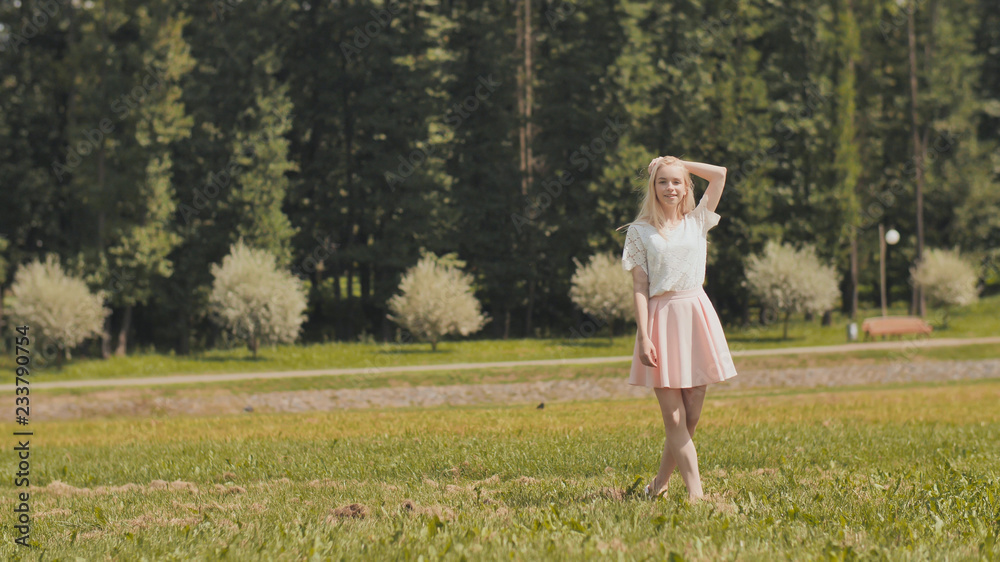 A happy young russian girl is running in the city park.