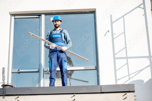 Portraiit of a builder in uniform standing with level on the balcony of a new house on the construction site