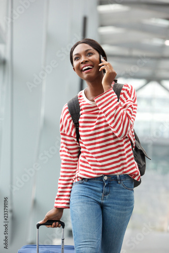 happy young african american woman walking and talking in airport terminal