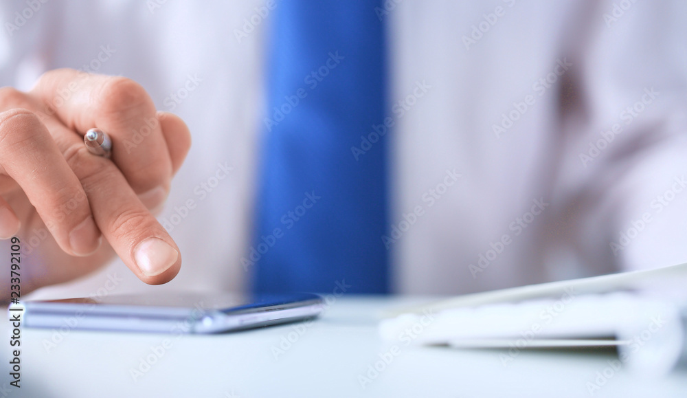 Fototapeta premium Businessman using smart phone in office close up.
