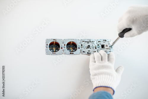 Close-up of an electrician mounting electric sockets on the white wall © rh2010